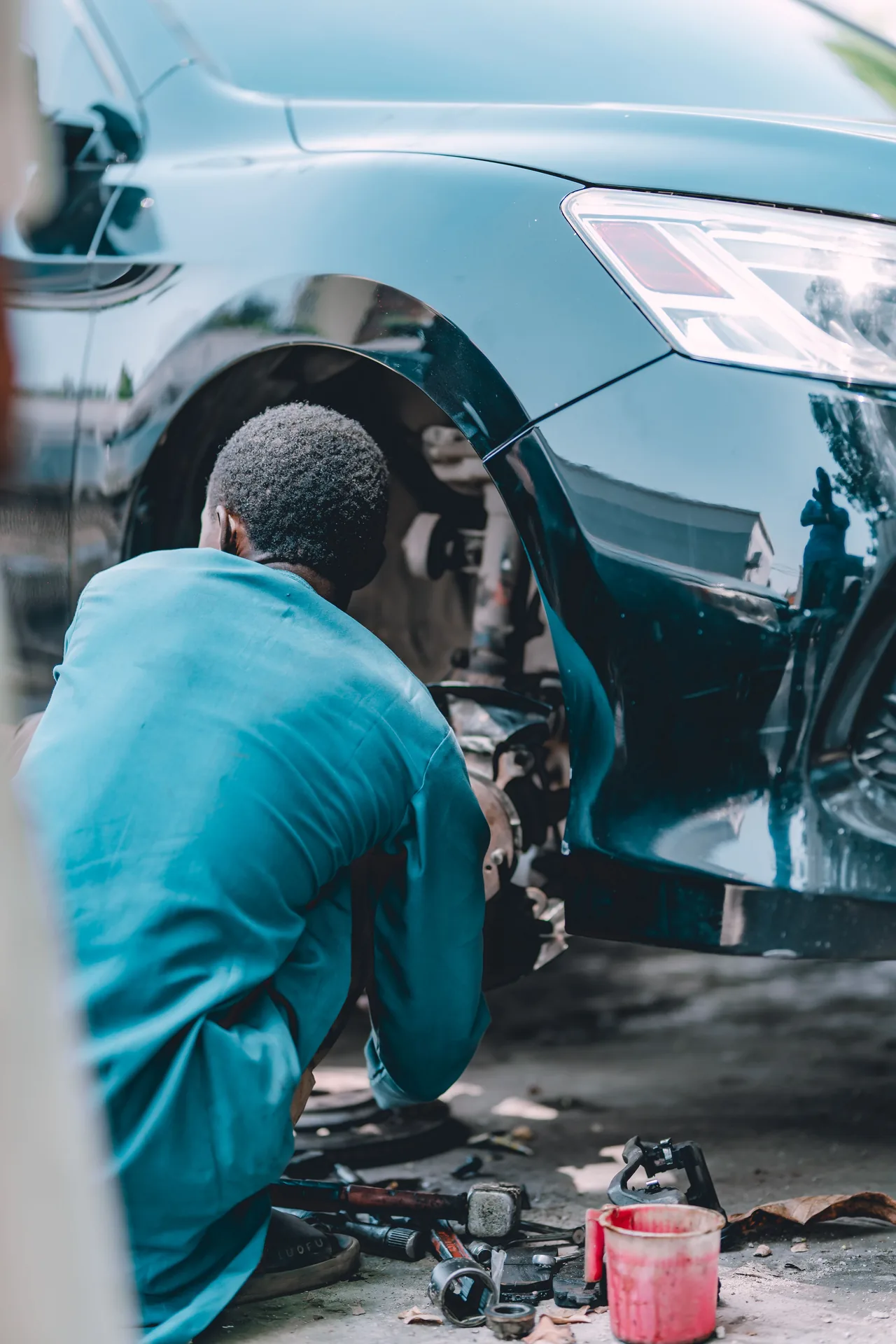 Techniker arbeitet am freigelegten Rad- und Bremsenbereich eines Autos