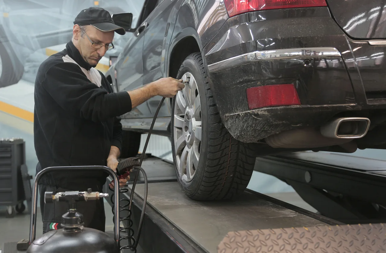 Mechaniker kontrolliert den Reifendruck eines angehobenen Autos